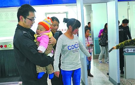 重慶江北機場安檢門通道工作員抱小孩兒助乘客安檢[圖]